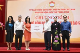 Chủ tịch Ủy ban Trung ương Mặt trận Tổ quốc Việt Nam Đỗ Văn Chiến tiếp nhận bảng tượng trưng số tiền từ Thứ trưởng Bộ Ngoại giao, Chủ nhiệm Ủy ban Nhà nước về người Việt Nam ở nước ngoài Lê Thị Thu Hằng. (Ảnh: TTXVN phát)