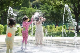 Trẻ em giải nhiệt dưới đài phun nước tại Daegu, Hàn Quốc. (Ảnh: Yonhap/TTXVN)