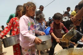 Trẻ em nhận thực phẩm cứu trợ tại thành phố Rafah, Dải Gaza ngày 19/5. (Ảnh: THX/TTXVN)