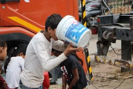 Người dân vội vàng uống nước ngay sau khi hứng được từ xe bồn của chính phủ. (Ảnh: Ngọc Thúy/TTXVN)