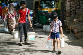 Các em nhỏ lấy nước tại điểm cấp nước công cộng ở New Delhi, Ấn Độ. (Ảnh: AFP/TTXVN)