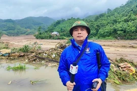 Phóng viên Hồng Ninh, Cơ quan thường trú Lào Cai tác nghiệp khu vực thảm họa lũ quét tại làng Nủ, xã Phúc Khánh, huyện Bảo Yên (Lào Cai). (Ảnh: TTXVN)