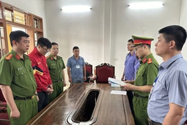 Cơ quan Cảnh sát điều tra, Công an tỉnh Sơn La tổ chức thi hành các quyết định tố tụng đối với Lò Minh Phương (áo đỏ). (Ảnh: TTXVN phát)