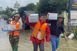 Các lực lượng chức năng và người dân chuẩn bị lương thực hỗ trợ bà con vùng ngập lụt. (Ảnh: Thanh Thuỷ/TTXVN)