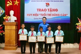 Phó Bí thư Tỉnh Đoàn, Chủ tịch Hội đồng Đội tỉnh Quảng Bình trao tặng Huy hiệu Tuổi trẻ dũng cảm cho 5 em học sinh. (Nguồn: Báo Pháp Luật)