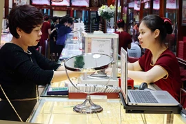 Người dân mua bán vàng tại một cửa hàng kinh doanh vàng Bảo Tín Minh Châu. (Ảnh: Trần Việt/TTXVN)