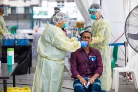 Nhân viên y tế lấy mẫu xét nghiệm COVID-19 cho người dân tại Singapore hồi năm ngoái. (Ảnh: AFP/TTXVN)