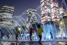 Trẻ em vui chơi dưới đài phun nước dọc sông Hàn ở Thủ đô Seoul (Hàn Quốc). (Ảnh: Yonhap/TTXVN)