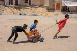 Các em nhỏ vận chuyển nước tại Khan Younis, Dải Gaza, ngày 31/5/2024. (Ảnh: THX/TTXVN)