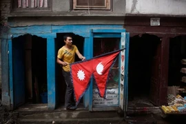 Một người dân cầm lá quốc kỳ Nepal bên ngoài quầy hàng của mình ở Kathmandu. (Nguồn: AP/CNN)