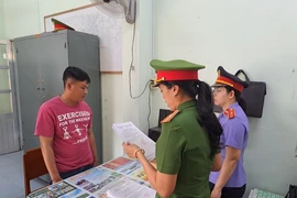 Lực lượng chức năng tống đạt các Quyết định và Lệnh bắt tạm giam đối tượng Phan Thành Được (trái, áo đỏ). (Ảnh: TTXVN phát)