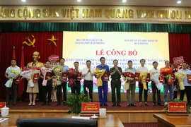 Ông Lê Trung Kiên, Trưởng ban Ban quản lý Khu kinh tế Hải Phòng (thứ 6 từ trái sang) và Đại tá Bùi Xuân Thắng (mặc quân phục) chúc mừng các doanh nghiệp. (Ảnh: Minh Thu/TTXVN)
