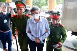 Lực lượng chức năng dẫn giải bị cáo Nguyễn Thanh Long (cựu Bộ trưởng Bộ Y tế) đến phiên tòa. (Ảnh: Phạm Kiên/TTXVN)