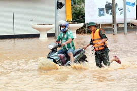 Bộ đội hỗ trợ người dân di chuyển qua khu vực ngập lụt tại thành phố Sơn La. (Ảnh: Quang Quyết/TTXVN)