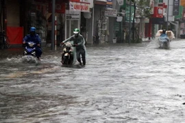 Nước ngập tại nhiều tuyến đường trong thành phố Huế khiến việc đi lại của người dân khó khăn. (Ảnh: Đỗ Trưởng/TTXVN)