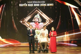 Bí thư Thành ủy Thành phố Hồ Chí Minh Nguyễn Văn Nên trao danh hiệu tôn vinh Nghệ sỹ Nhân dân Hùng Minh. (Ảnh: Thu Hương/TTXVN)