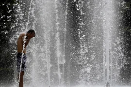 Người dân làm mát tại một đài phun nước ở Seville, Tây Ban Nha ngày 10/7/2023. (Ảnh: AFP/TTXVN)