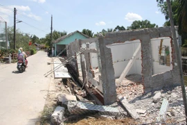 Một căn nhà của người dân ở thị trấn Ngan Dừa (Hồng Dân, Bạc Liêu) bị sụt xuống sông do ảnh hưởng của hạn hán. (Ảnh: Chanh Đa/TTXVN)
