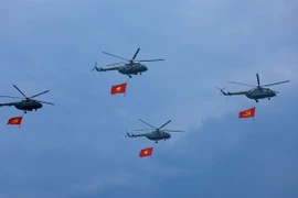 Máy bay trực thăng mang cờ Đảng, cờ Tổ quốc bay qua Lễ đài. (Ảnh: Dương Giang/TTXVN)