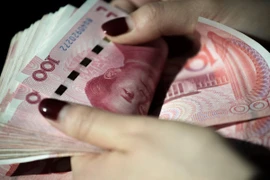 Kiểm tiền mệnh giá 100 Nhân dân tệ tại Bắc Kinh, Trung Quốc. (Ảnh: AFP/TTXVN)