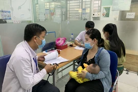 Phụ huynh đưa trẻ đi tiêm vaccine phòng bệnh sởi. (Ảnh: Đinh Hằng/TTXVN)