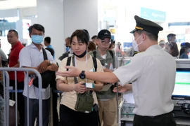 Nhân viên an ninh hàng không kiểm tra thủ tục giấy tờ đi máy bay của hành khách. (Ảnh: PV/Vietnam+)