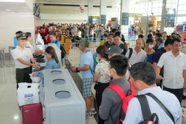 Nhân viên an ninh hàng không kiểm tra giấy tờ hành khách đi máy bay. (Ảnh: PV/Vietnam+)
