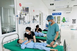Bác sỹ Trần Minh Long kiểm tra sức khỏe bệnh nhi sau ca phẫu thuật. (Ảnh: Bích Huệ/ TTXVN)