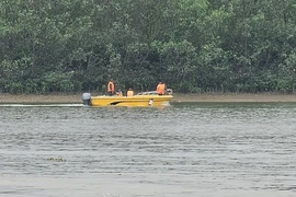 Lực lượng cứu hộ rà soát tại khu vực sông Chanh gần nơi các ngư dân gặp nạn. (Ảnh: TTXVN phát)