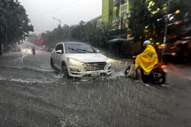 Người và phương tiện gặp nhiều khó khăn khi lưu thông qua các tuyến đường tại thành phố Đồng Hới (Quảng Bình) bị ngập sâu. (Ảnh: TTXVN phát)