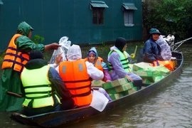 Dùng thuyền vận chuyển nhu yếu phẩm, nước sạch đến người dân các vùng thấp trũng còn bị ngập nước của huyện Lệ Thủy (Quảng Bình). (Ảnh: Tá Chuyên/TTXVN)