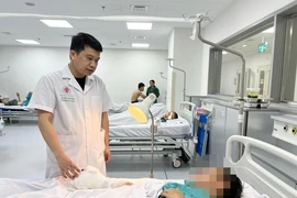 Bác sĩ Bệnh viện Trung ương Quân đội 108 khám, theo dõi sức khoẻ cho một bệnh nhân tại nạn do pháo nổ. (Ảnh: PV/Vietnam+)