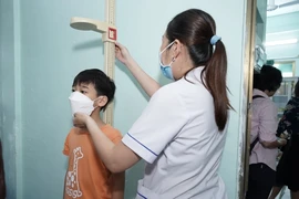 Nhân viên y tế đo chiều cao đánh giá mức độ tăng trưởng của trẻ. (Ảnh: PV/Vietnam+)