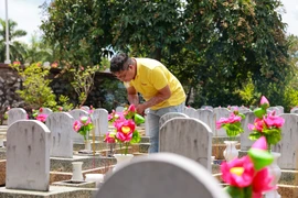 Cán bộ Báo Điện tử VietnamPlus thắp hương tại Nghĩa trang Liệt sỹ Quốc tế Việt-Lào. (Ảnh: Hoài Nam/Vietnam+)