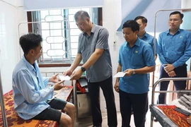 Ông Nguyễn Minh Dũng trao hỗ trợ các công nhân bị tai nạn. (Ảnh: Công Tường/TTXVN)
