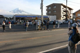Du khách chụp ảnh ngọn núi Phú Sĩ phía sau cửa hàng tiện lợi Lawson. (Nguồn: Mainichi)