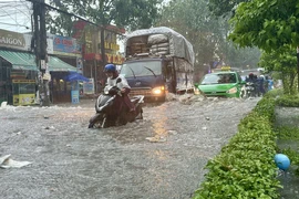 Người dân di chuyển qua điểm ngập tại ngã ba Trảng Dài (thành phố Biên Hòa, Đồng Nai). (Ảnh: Lê Xuân/TTXVN)