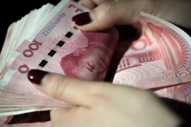 Kiểm tiền mệnh giá 100 nhân dân tệ tại thủ đô Bắc Kinh, Trung Quốc. (Ảnh: AFP/TTXVN)