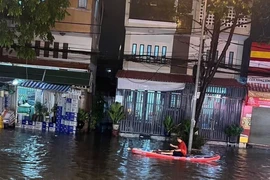 Người dân phải dùng thuyền để di chuyển tại khu vực ngã ba cống trên đường Thích Quảng Đức, thành phố Thủ Dầu Một, tỉnh Bình Dương. (Ảnh: TTXVN phát)