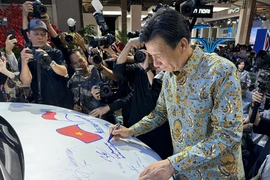 Đại sứ Việt Nam tại Indonesia Tạ Văn Thông ký tên vào chiếc xe trưng bày của Vinfast. (Ảnh: Đỗ Quyên/Vietnam+)