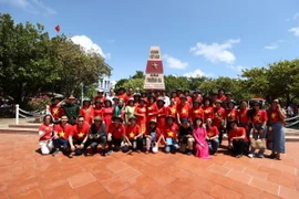Đoàn đại biểu kiều bào chụp ảnh tại cột mốc của quần đảo Trường Sa. (Ảnh: TTXVN)