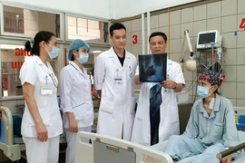 Phó Giáo sư-Tiến sỹ-bác sỹ Trần Mạnh Hùng (mặc áo blue, cầm phim X.Q) và êkip phẫu thuật thăm khám cho bệnh nhân K.V.S. (Nguồn: Bệnh viện Bạch Mai)