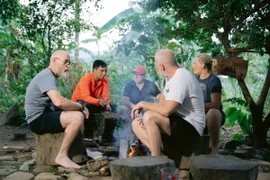 Du khách quốc tế thư giãn quanh bếp lửa hồng ở bản Rum Ho, xã Kim Thủy, huyện Lệ Thủy, tỉnh Quảng Bình. (Ảnh: Mạnh Thành/TTXVN)