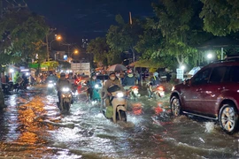 Các phương tiện di chuyển khó khăn khi triều cường gây ngập trên đường Trần Xuân Soạn, quận 7. (Ảnh: Hồng Giang/TTXVN)