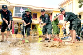 Cán bộ chiến sỹ Công an các địa phương huyện Lệ Thủy tập trung tổng dọn, đẩy bùn đất sau lũ. (Ảnh: TTXVN phát)