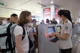 Nhân viên an ninh hàng không kiểm tra giấy tờ hành khách trước khi vào khu vực soi chiếu. (Ảnh: Huy Hùng/TTXVN)