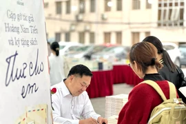 Tác giả Hoàng Nam Tiến ký tặng sách cho độc giả tại Hội sách Nhã Nam (Hà Nội) ngày 9/4. (Ảnh: PV/Vietnam+)