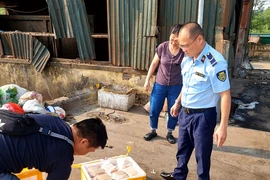 Lực lượng Quản lý Thị trường kiểm tra số xúc xích thu giữ trên địa bàn huyện Thanh Trì. (Ảnh: PV/Vietnam+)
