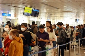 Hành khách xếp hàng làm thủ tục soi chiếu kiểm tra an ninh tại sân bay Tân Sơn Nhất. (Ảnh: Quang Châu/TTXVN)
