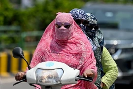 Người dân trùm kín tránh nắng nóng khi di chuyển tại Raipur, Ấn Độ ngày 15/4/2024. (Ảnh: AFP/TTXVN)